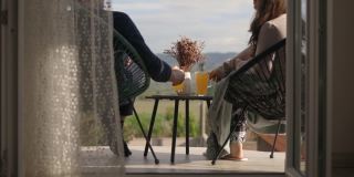 一对夫妇坐在阳台上，一边聊天一边喝果汁