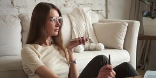 女企业家在家为客户录语音信息。女坐在沙发旁，给上网