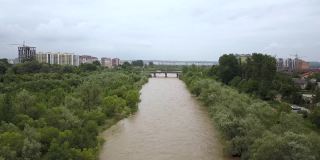 鸟瞰图宽阔的肮脏的河流与浑浊的黄色的水流经一个城市在洪水期间在春季大雨。