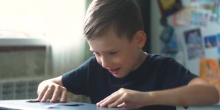 开朗开朗的白人男孩在家里打开笔记本电脑，开始学习。一个6-8岁的孩子正在使用笔记本电脑。远程学习学生主题。有选择性的重点