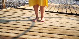 一个女人光着脚走在海上的旧木码头上
