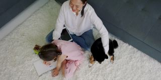 亚洲妈妈和女儿在家里快乐地和狗玩耍