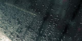 雨水滴在汽车的玻璃窗上慢慢地落下。