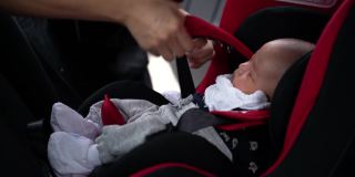 母亲在汽车安全座椅上为婴儿系安全带