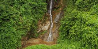 鸟瞰图小瀑布流经常绿森林的岩石悬崖。泰国北部