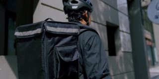 背包工作的送货员骑着自行车在城市里为客户和客户送订单。