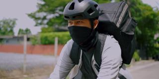 亚洲人在城市里骑自行车送食物。