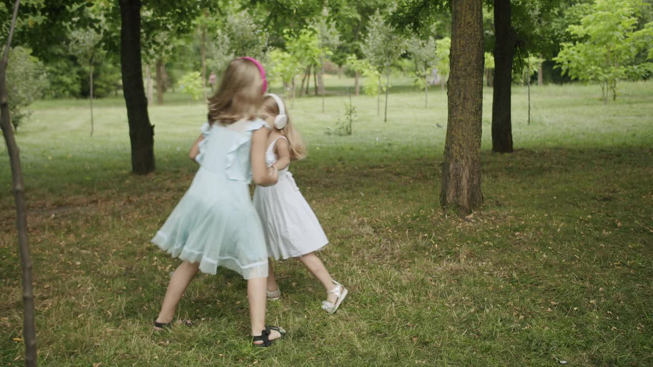 快乐的孩子们在公园里跳舞和听音乐，姐妹们轮流白天的模式