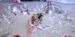 精美的圆桌安排在婚礼上，水晶葡萄酒和香槟酒杯和银餐具在象牙桌布上。餐桌中央摆着一束杏花。时尚的节日婚礼装饰，精美
