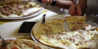 人们手切意大利多汁的披萨与不同的配料和品尝，朋友聚会庆祝派对在当地地中海餐厅的披萨菜单。传统的意大利披萨店