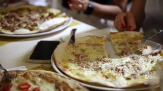 人们手切意大利多汁的披萨与不同的配料和品尝，朋友聚会庆祝派对在当地地中海餐厅的披萨菜单。传统的意大利披萨店视频素材模板下载
