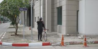 亚洲快递员走路，拖着自行车