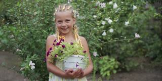 一个积极微笑的学龄女孩手里拿着花园里美丽的花朵。一个真正的孩子气的微笑。这个孩子从事园艺。
