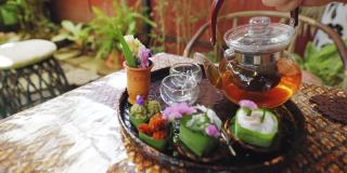 透明茶杯中的花草茶，搭配Khanom Tako，泰式椰子布丁，Khanom Chan，泰式分层甜点，