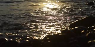 在金色的夕阳下，海浪涌向卵石滩