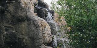 水从石头上流下，形成一个小瀑布。用慢动作拍摄水流