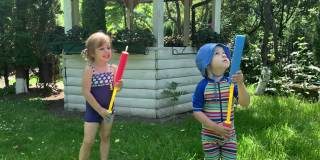 可爱的快乐的孩子，学龄前的小女孩和男孩的孩子玩有乐趣的水泵枪在外面。阳光明媚，公园里的一天。儿童后院花园游戏。夏天，运动，假期，家庭，童年