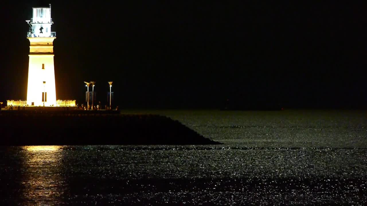 夜晚的灯塔，月光反射在海面上。