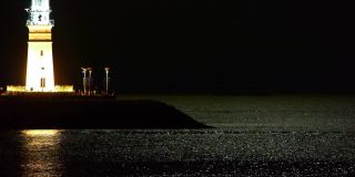 夜晚的灯塔，月光反射在海面上。