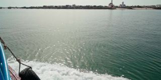 岛de Farol。阿尔加维。葡萄牙。在海洋上乘船旅行。海面上风平浪静，海浪拍打着船。背景中的灯塔
