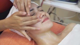女性与美丽的皮肤正在被按摩师在一个放松的心情面部按摩。水疗中心的按摩师们正在给脸部敷面膜，以恢复活力和面部护理。视频素材模板下载
