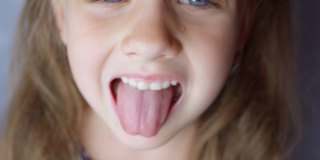 女孩张大嘴巴，伸出长长的舌头。孩子露出柔软的牙齿