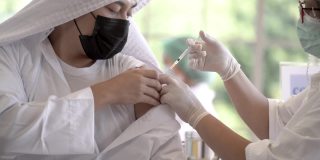 一名阿拉伯穆斯林男子在诊所或医院接种新冠疫苗时的表情，在注射疫苗以获得保护病毒的免疫力后，护手在手臂上用防洗膏药覆盖。
