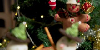 照片:在一间装饰着圣诞树的公寓里，有两个自制的冰霜雪人杯形蛋糕，用冰霜球做的，黑巧克力饼干，绿色奶油做的帽子，粉色的鼻子和巧克力球做的绿色纽扣，椒盐卷饼棒做的手臂
