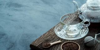 工艺泡茶，将热腾腾的茶水从茶壶倒进茶杯里，放在深色厨房餐桌背景的旧木板上，静物放松时光的深色心情风格。