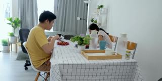 亚洲孩子在家里一起用智能手机看电影或视频时吃早餐，生活理念。