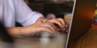 镜头滑过在咖啡馆里用笔记本电脑键盘打字的女自由职业者的手。女商人在办公室工作与互联网。女人在咖啡店上网找新工作。经营理念