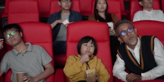 一位亚洲华人爷爷和他的孙子们喜欢在电影院看电影。