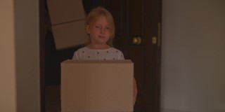 一个年轻的家庭带着一个孩子搬着纸板箱进了他们的新家