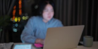 一个亚洲女人用笔记本电脑加班到深夜