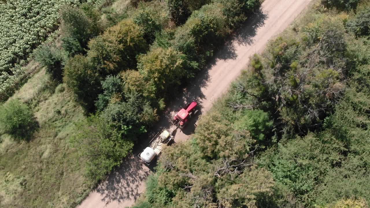 拖拉机和喷雾器在乡村道路上。农用机械在田间的碎石小道上行驶。拖拉机与臂架喷雾器在阳光明媚的田野。农业的概念