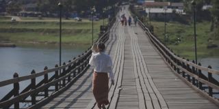 女人走在僧伽拉布里的桥上，北碧里美丽的日出