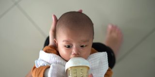 亚洲婴儿喝奶瓶里的牛奶