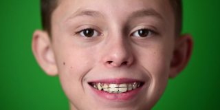 孩子戴上牙齿矫正板，绿色背景上是孩子的肖像。