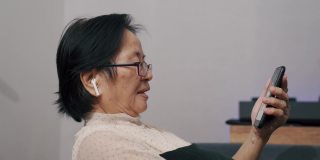 奶奶在家里用智能手机和孙子聊天。