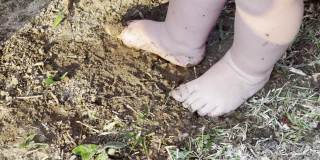 可爱的凌乱的婴儿脚踩在泥与水
