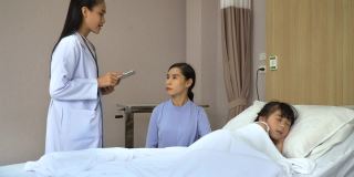亚洲女孩病人睡在床上，医生在医院用药片向母亲解释女儿的病情