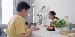 亚洲孩子在家里一起用智能手机看电影或视频时吃早餐，生活理念。