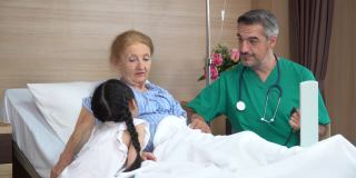 在病房里，医生正和躺在床上陪孙女的老年女病人交谈。物理治疗师探访及与残疾老年女性进行物理治疗。