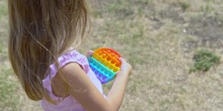 穿粉红色衣服的女孩扮演波普尔。孩子热衷于彩虹抗压力。孩子的硅胶玩具
