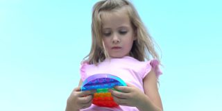 穿粉红色衣服的女孩扮演波普尔。孩子热衷于彩虹抗压力。孩子的硅胶玩具