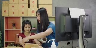 亚洲妇女和小女孩展示和包装盒集装箱网上销售在家里。