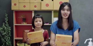 亚洲妇女和小女孩展示和包装盒集装箱网上销售在家里。