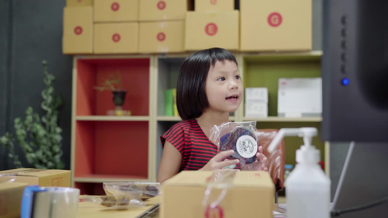 小女孩展示和包装盒容器网上销售在家里。