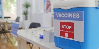 现代冠状病毒疫苗接种中心的办公桌上装有Covid-19疫苗的冷藏容器