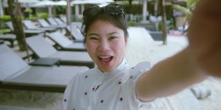 迷人的亚洲女性旅行者穿着休闲布夏季周末假期手握智能手机视频通话社交媒体与朋友的快乐和幸福在海滩海洋自然背景